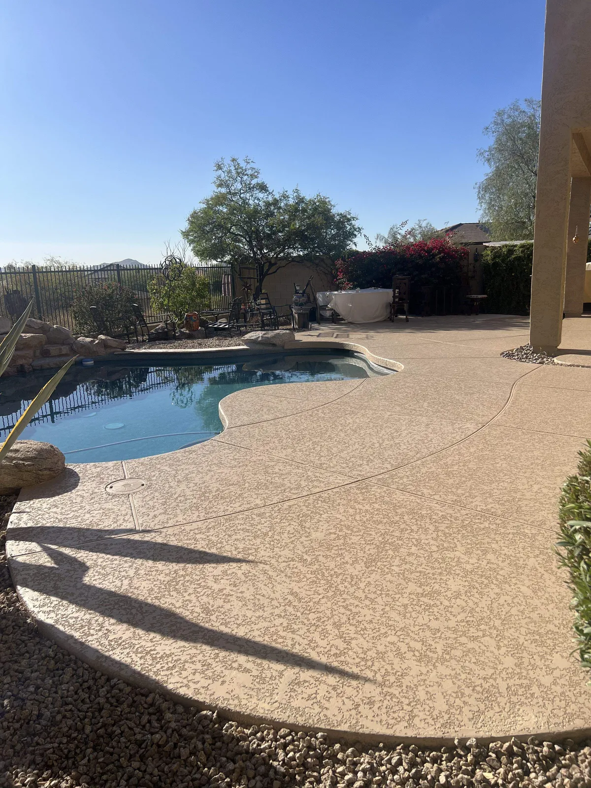 Two-tone tan acrylic lace pool deck after resurfacing, same desert-view backyard