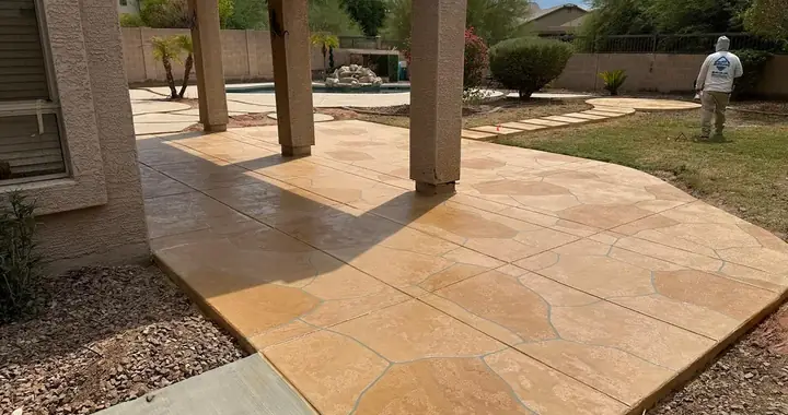 Tan flagstone coating on a covered patio slab, crew finishing the edges