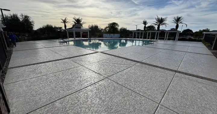 Light textured community pool deck with saw-cut joints, gazebos, and handrails