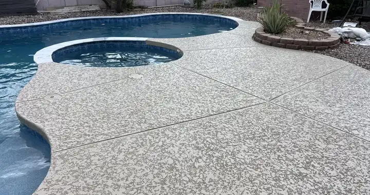 Freshly resurfaced light deck around a pool and raised spa, next to a gravel planter bed