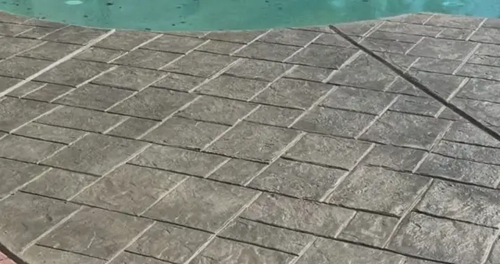 Gray stamped ashlar-pattern deck meeting a curved pool edge